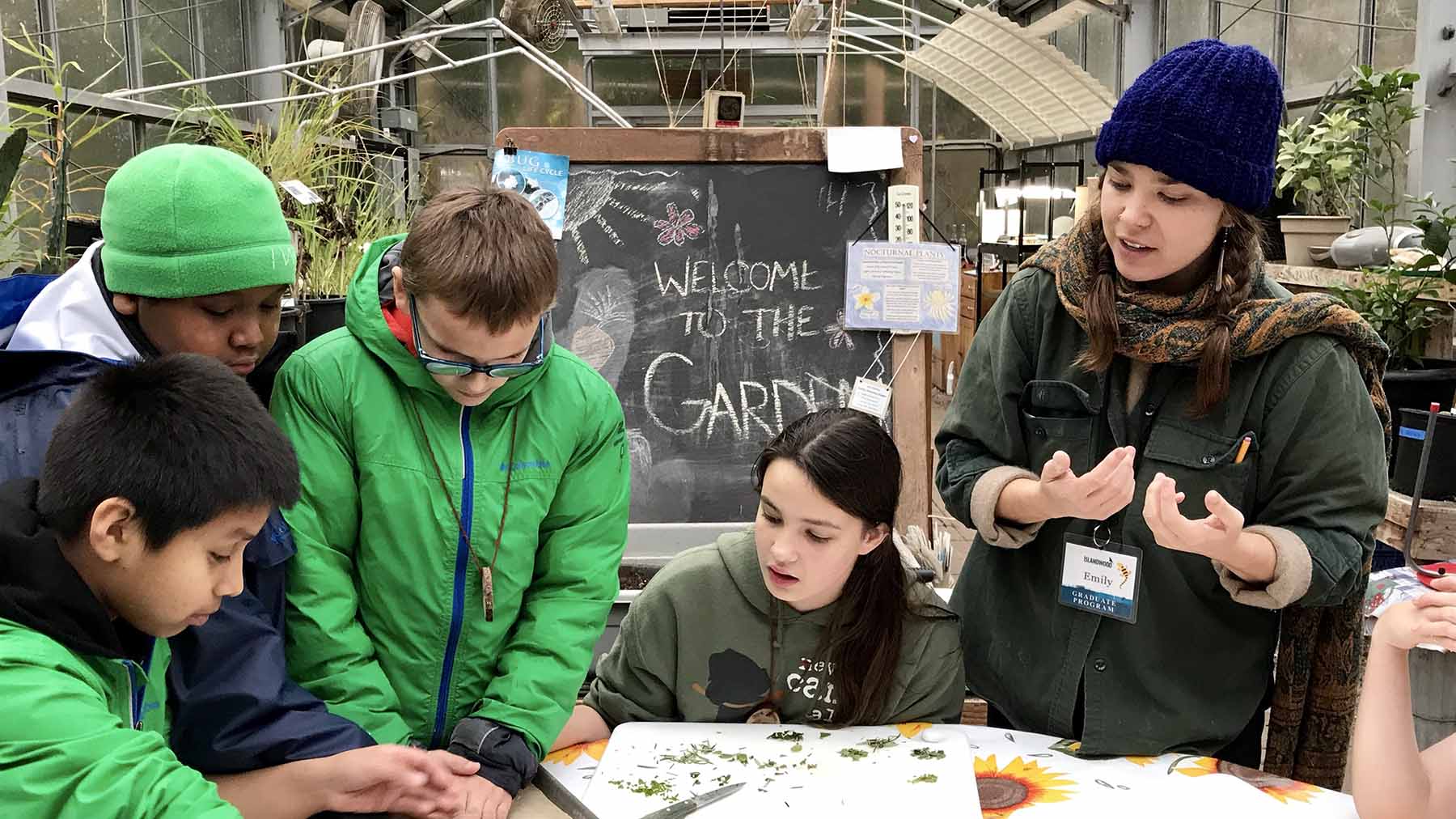 Graduate student teaching children in a greenhouse