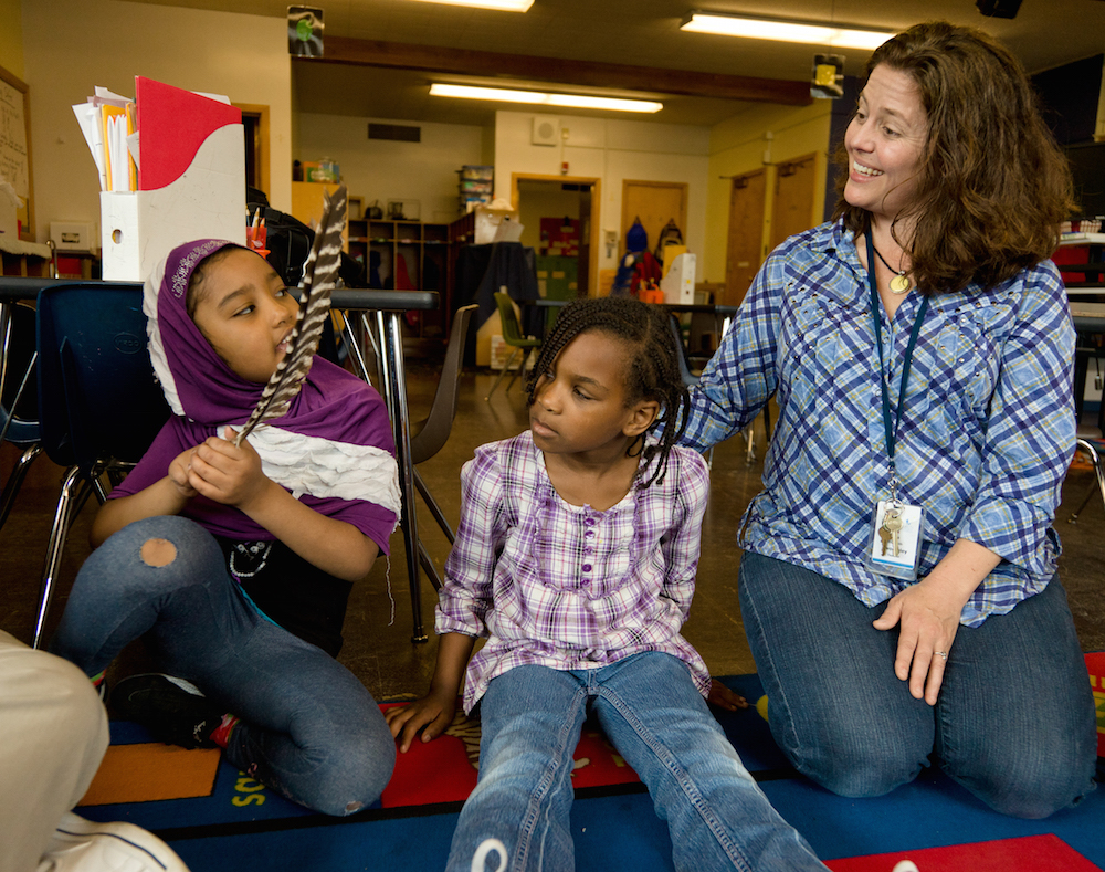 Educator speaking with two young children in a school building