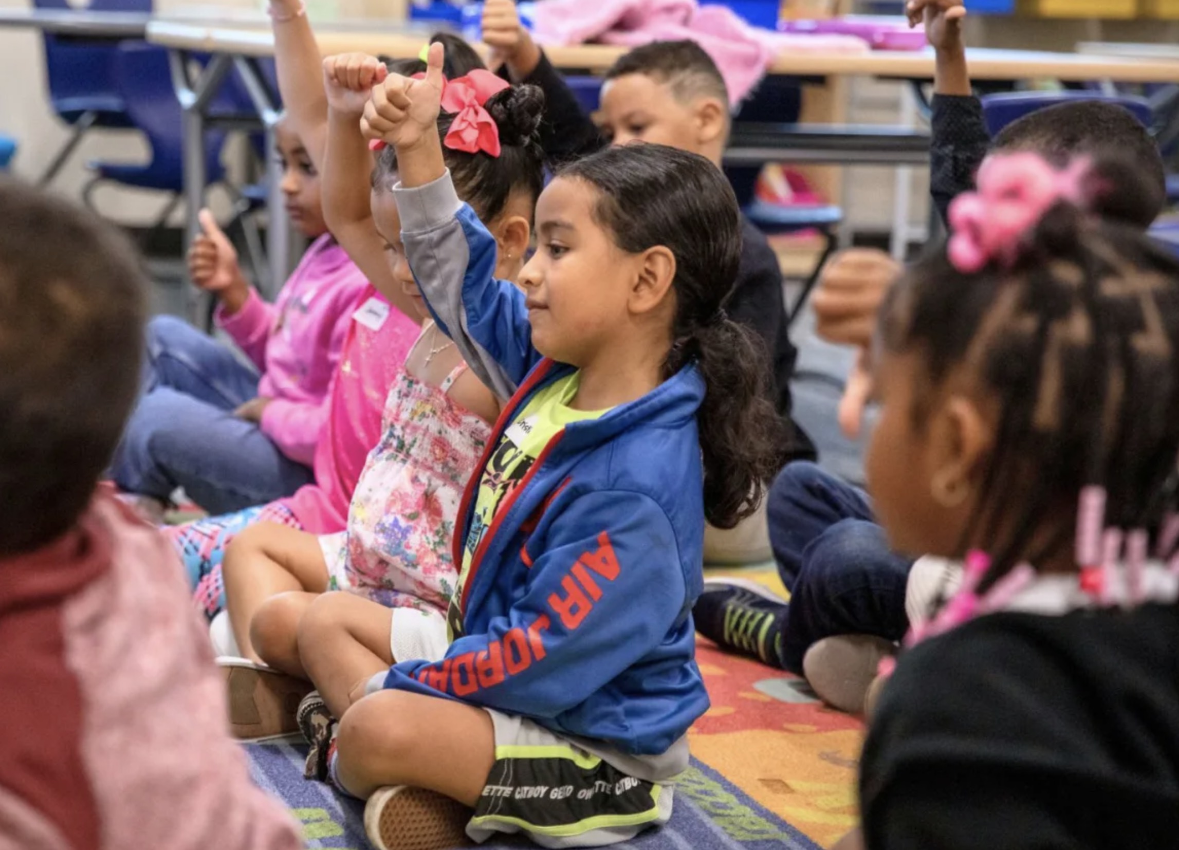 Young student raise their hand in an elementary classroom